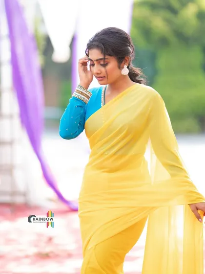 A different pose in the same yellow saree, capturing a moment of thought and highlighting the flow of the fabric.