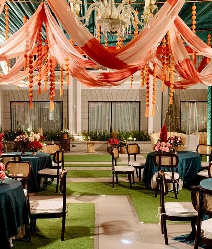 Guest seating at the Moroccan event, with teal tablecloths providing a cool contrast to the warm orange and red tones of the draped ceiling.