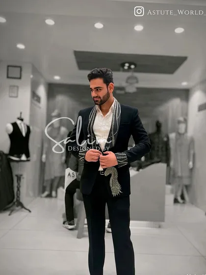 A client in a black suit with a unique scarf-like embroidered lapel. This is a fashion-forward design that blends accessories and the garment into one.
