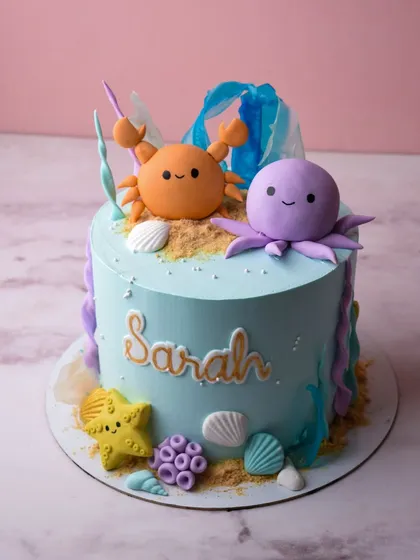 An underwater adventure for little Sarah's birthday. This cake is decorated with cute fondant sea creatures like a crab and an octopus, along with shells, starfish, and edible sand for a fun ocean theme.