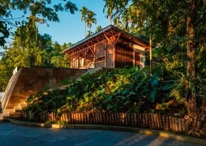 The restaurant pavilion, elevated on a stone plinth and surrounded by lush landscaping, creating a dining experience immersed in nature.