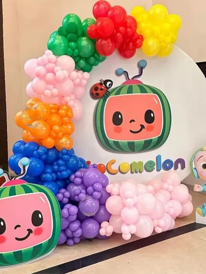 A simple and cute Cocomelon themed setup. This decoration uses a circular backdrop with the Cocomelon logo, character cutouts, and a colorful balloon garland.