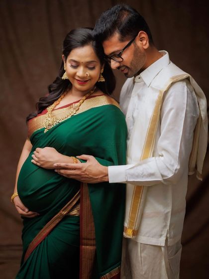 A graceful maternity portrait showcasing South Indian tradition. The rich green and gold saree beautifully complements the glow of the mother-to-be.