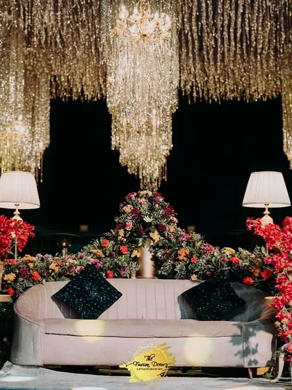 For a Sangeet that truly shines, I love to play with light and texture. This stage is a masterpiece of glamour, featuring a cascade of shimmering tinsel that catches the light beautifully, set against a backdrop of rich, deep red florals. It’s the perfect stage for a night of music and dance.