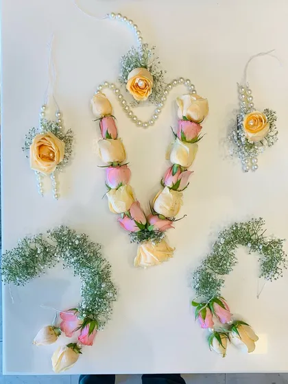 This is one of my complete fresh flower jewelry sets, perfect for a bride's haldi or mehndi ceremony. It features a floral haar made with delicate pink and peach rose buds, matching hathphool for both hands, elegant karn phool earrings, and a maang tikka. I have woven in sprigs of baby's breath and delicate pearl strings to create a look that is both traditional and soft. Each piece is handcrafted to feel lightweight and comfortable throughout your event.