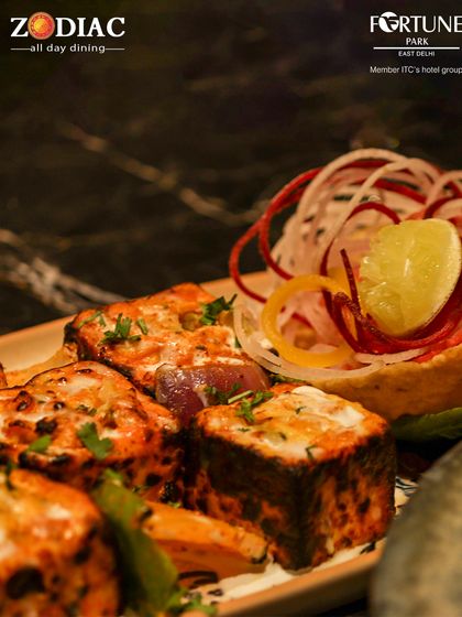 Our Paneer Tikka is marinated in flavorful spices and grilled to achieve the perfect char, served with a garnish of fresh onions.