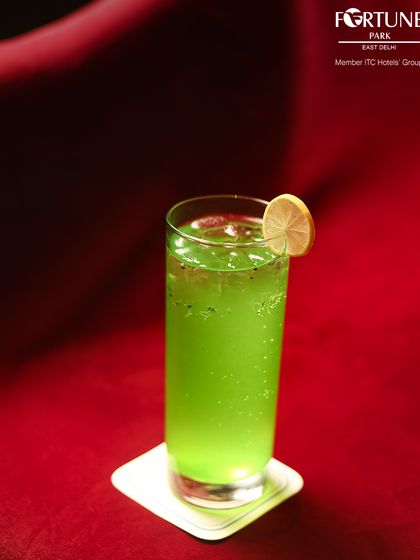 A vibrant green mocktail, served against a rich red backdrop, showcasing the bold colors and refreshing flavors of our non-alcoholic beverage selection.