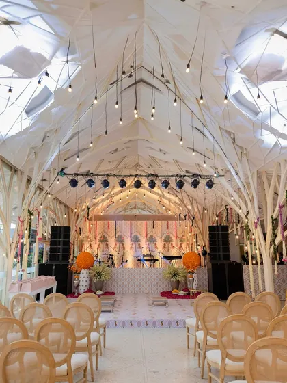 A beautiful indoor Mehendi setup, transforming the space with pastel lounges, marigold accents, and traditional garlands for a "pooja to party" vibe.