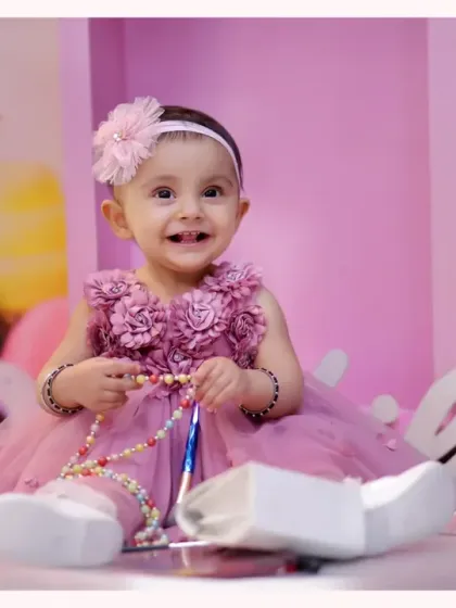 A happy smile from a baby girl during her candy-themed photoshoot. The background features giant ice cream cones and macarons, creating a sweet and colorful setting.