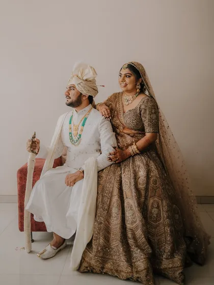 Another angle of the regal seated portrait, showcasing the full splendor of the bride's lehenga and the groom's traditional attire.