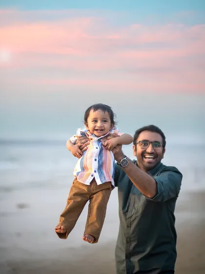 Pure happiness! A father joyfully lifts his son into the air against a beautiful sunset sky. This is a moment of pure, uninhibited fun.
