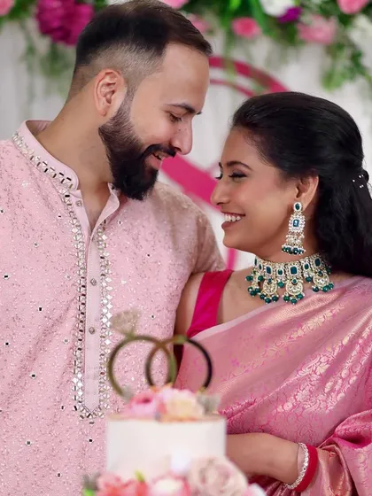 A picture-perfect moment by the cake. Her makeup is soft and radiant, with defined eyes and a warm smile that lights up the photo.