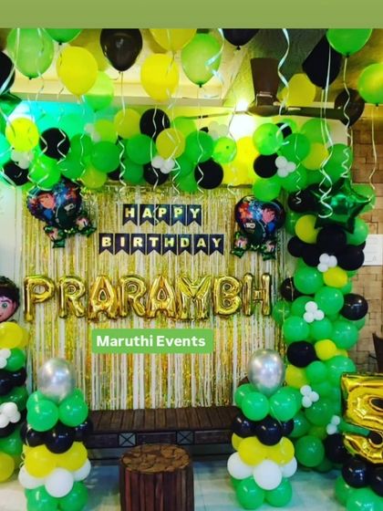 A Ben 10 themed party in signature green, black, and yellow. The setup includes a foil curtain backdrop and character balloons.