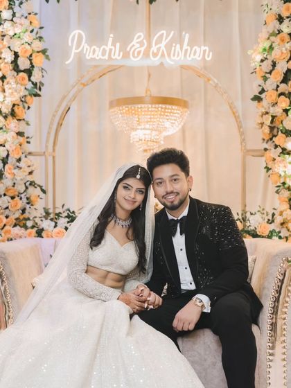 A perfect portrait of the newly engaged couple. Seated on a couch with a neon sign of their names, they smile for the camera, radiating happiness.