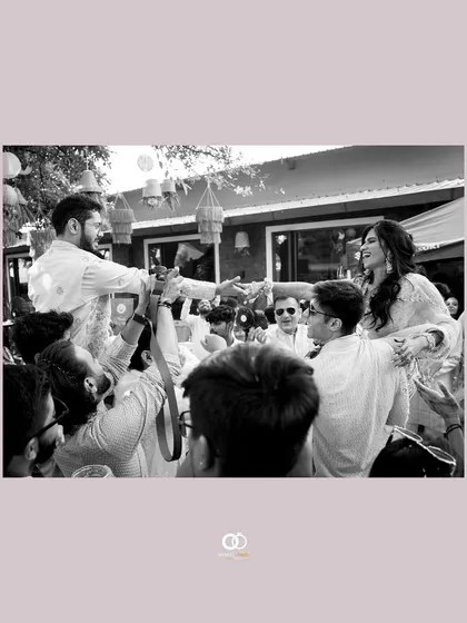 A black and white shot of the couple being lifted up by their friends during a joyous and energetic Haldi celebration.