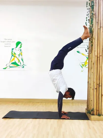 This is a wall-assisted handstand, another progressive step in building strength for inversions. My coaching method involves breaking down complex poses into manageable steps, making them accessible and safe for you to explore.