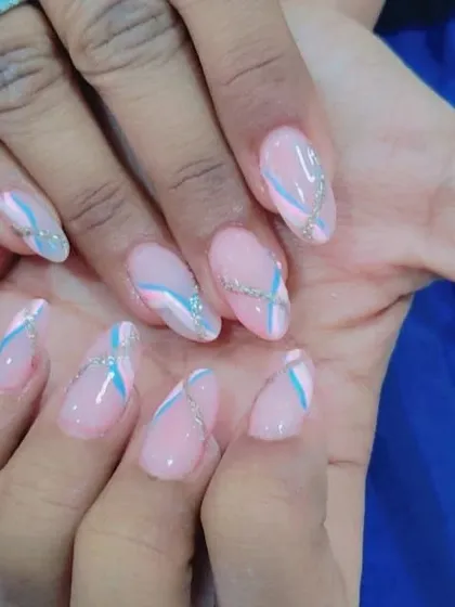 This is an abstract design on almond-shaped nails. I used a sheer pink base and added delicate swirls of blue, white, and silver glitter for a unique, artistic look.