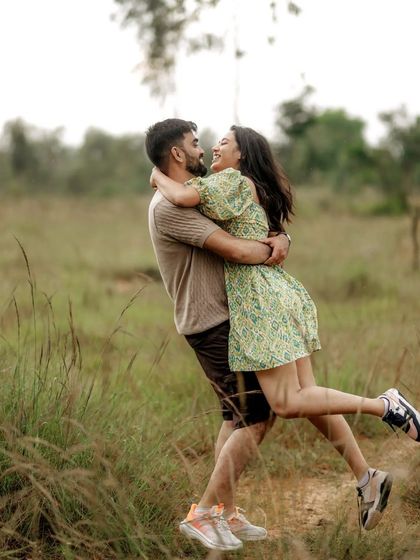 A joyful, candid shot of a couple in a field, with the groom lifting the bride in a happy embrace.