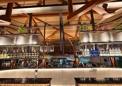 The bar at KGA illuminated at night. The warm lighting highlights the architectural details and the integrated planters, creating a sophisticated and inviting ambiance for evening gatherings.