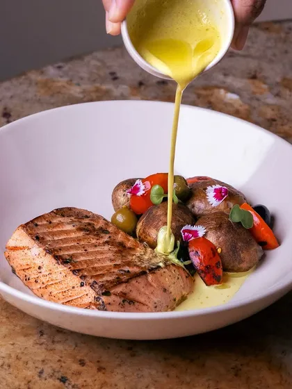 The final pour of a creamy Ceylon coconut curry over our Dutch oven-baked salmon, bringing a taste of Sri Lankan paradise to your plate.