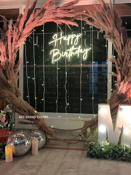 A close-up shot of the rustic birthday decor, showing the texture of the pampas grass and the warm lighting from the neon and marquee signs.