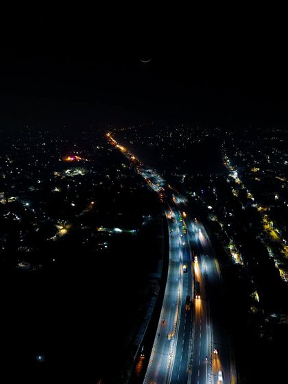 An aerial night shot of a highway in Kanpur, looking like a road to infinity. The long streaks of light from traffic create a futuristic and mesmerizing cityscape.