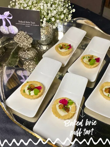 Baked Brie Puff Tarts, each individually plated on a modern white dish, garnished with edible flowers for a touch of elegance.