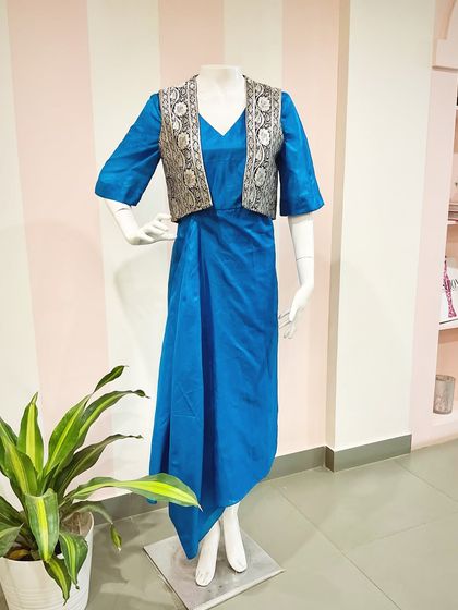 The complete upcycled outfit: a vibrant blue dress with an elegant drape, paired with a structured jacket made from the saree's brocade pallu.