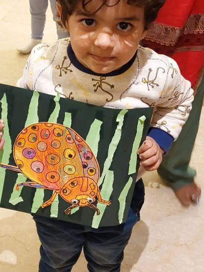 A young student proudly shows off the colorful ladybug he created. This project is great for learning about insects and practicing fine motor skills.