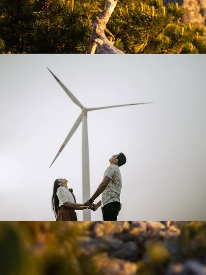 A couple holding hands and looking up at a windmill, a shot that symbolizes looking towards the future together.
