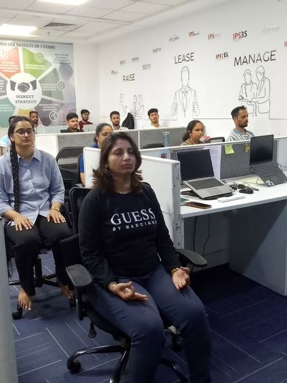 Employees at their desks practicing seated meditation. This shows how seamlessly yoga and mindfulness can be integrated into the corporate environment without disrupting the workspace.