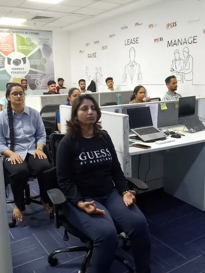 Employees at IPS Group in Goregaon practice seated meditation at their desks. This demonstrates how easily yoga and mindfulness can be integrated into the corporate setting without disrupting the workspace.