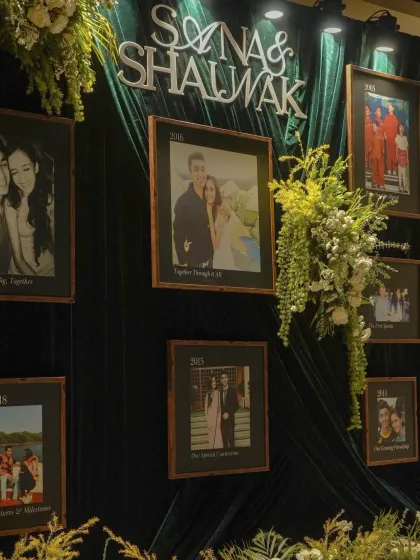 A deeply personal timeline wall created for a Sangeet. Set against an emerald velvet backdrop, framed photos tell the couple's love story through the years, creating a beautiful conversation piece.