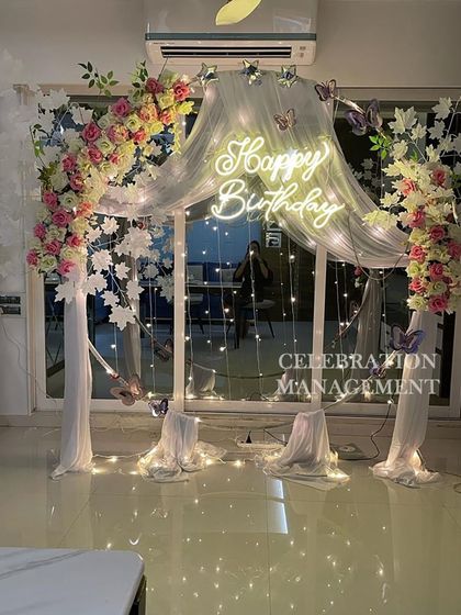 This angle shows how the fairy lights behind the drapes and the neon sign create a beautiful glow. The butterfly accents add a touch of whimsy to this enchanting birthday setup.