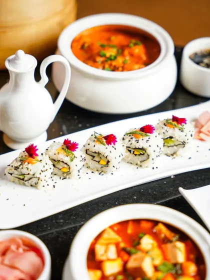 A beautiful spread of assorted sushi rolls and Asian curries. The clean, bright lighting and white porcelain dishes create an elegant and appetizing look for a restaurant menu.