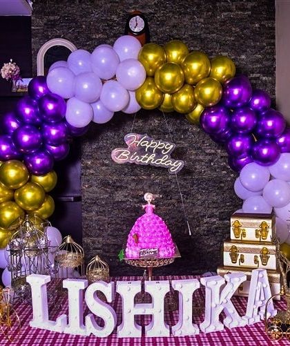 A closer look at the 'Lishika' birthday setup, focusing on the decor elements. This view highlights the purple and gold balloon arch, marquee letters, and a doll-themed cake, showing how we create a complete, themed look even in a small space.