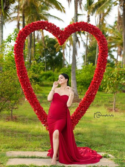 A stunning solo portrait in a red fabric wrap, framed by our red floral heart prop. The pose is elegant and powerful.
