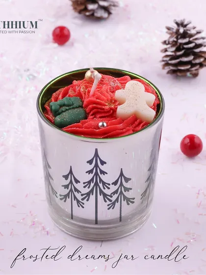 A silver jar with pine tree designs, topped with a gingerbread man.