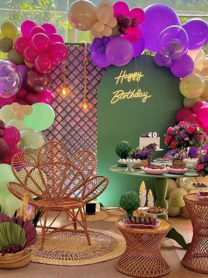 A beautiful and bohemian-chic 40th birthday party. This outdoor setup includes a unique color palette, a stylish peacock chair, and modern floral arrangements.