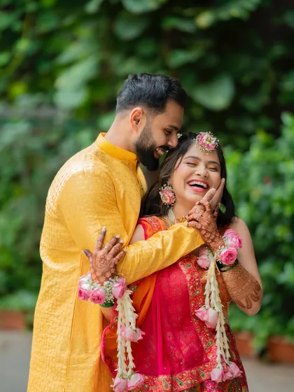 A moment of pure, uninhibited laughter during a Haldi shoot, showing the groom playfully applying haldi to the bride.