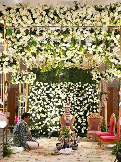 A breathtaking floral mandap for a day wedding. The structure was adorned with thousands of white flowers and lush greenery, with elegant swans and chandeliers adding a touch of fairytale magic.