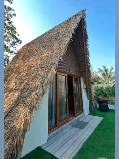 Another view of our popular A-Frame cottage, showcasing its charming thatched roof and private garden entrance under a clear blue sky.