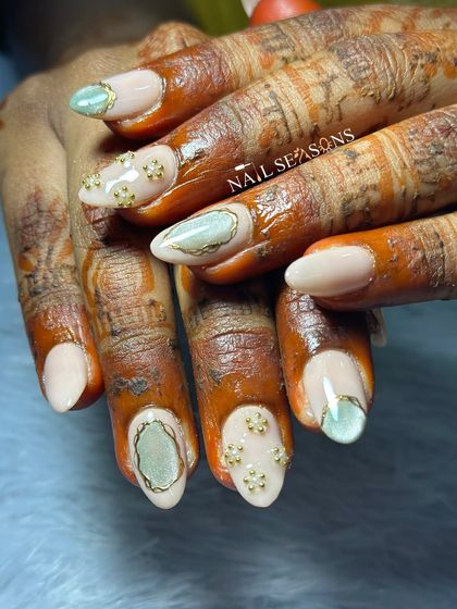 For this bride, we created a subtle and luxurious look with a nude base, soft green cat eye stones, and delicate gold floral embellishments.