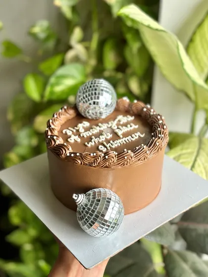 A side view of the disco ball cake, showing its smooth chocolate frosting and fun, celebratory theme.
