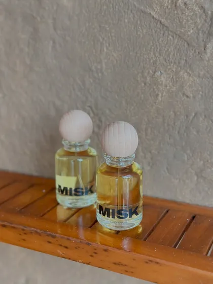 Two of my inspired perfumes sitting on a wooden shelf. The clear glass bottle lets you see the color of the perfume oil, which varies from scent to scent.