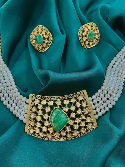 Intricately designed with genuine emeralds and pearls, this stunning choker is a testament to luxury. The gold filigree work adds a layer of sophistication, making it a perfect centerpiece for a bridal look.