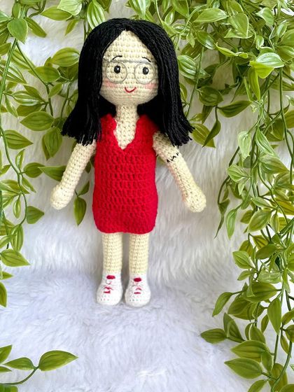 A thoughtful farewell gift for a niece heading off to higher studies. This replica doll in a red dress stands with her pet cat on a display base, a reminder of home she can take with her.