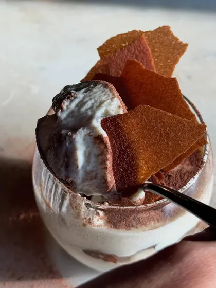A spoonful of our Tiramisu, showcasing its light, creamy texture and the crisp shards on top.