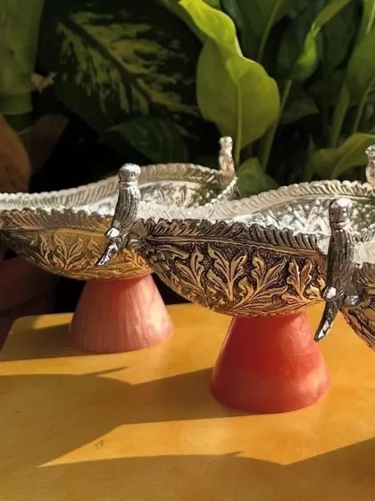 These German silver bowls with a unique parrot motif are perfect for serving dry fruits or sweets during festive occasions. The resin base adds a pop of modern color to the traditional design.