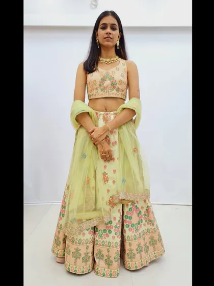 A full frontal view of the pastel green floral embroidered lehenga, showing the sleeveless blouse and the light net dupatta.